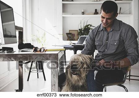 Young Man Sitting At Desk Stroking Dog Stock Image Errf00373