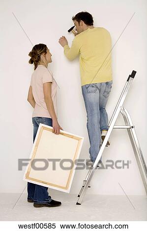 Stock Image Of Young Hanging Up Painting Man Standing On Stock Image Young Hanging Up Painting Man Standing On Ladder Fotosearch