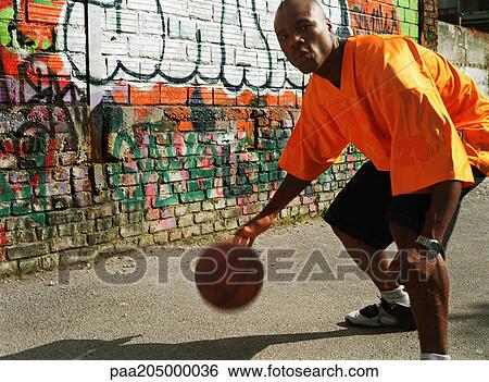 Man dribbling basketball next to graffitied wall, close-up View Large Photo Image Stock Photograph - Man dribbling basketball next to graffitied wall, close-up. Fotosearch