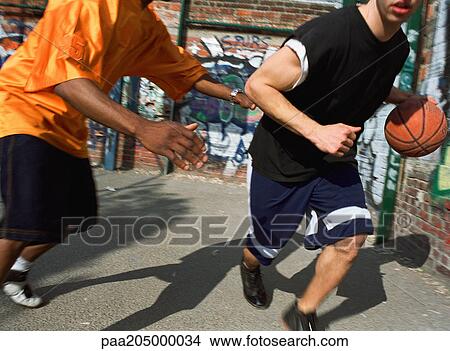 Man dribbling basketball, opponent blocking, next to graffitied wall View Large Photo Image Picture - Man dribbling basketball, opponent blocking, next to graffitied wall. Fotosearch