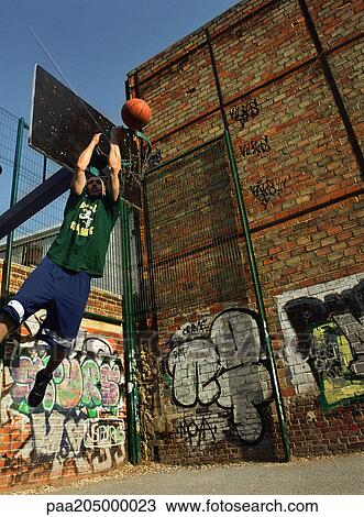 Man dunking basketball backwards in urban playground View Large Photo Image Stock Image - Man dunking basketball backwards in urban playground. Fotosearch