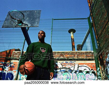 Man holding basketball in front of hoop and graffitied wall View Large Photo Image Stock Photo - Man holding basketball in front of hoop and graffitied wall. Fotosearch