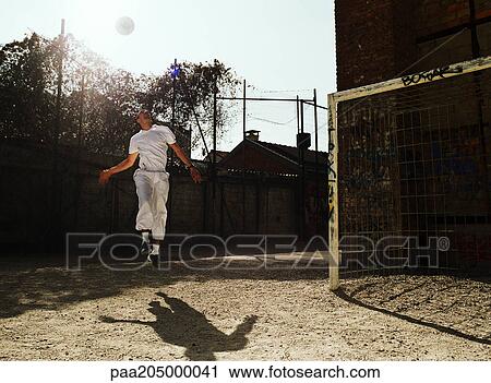 Stock Image - Man in air with soccer ball. Fotosearch