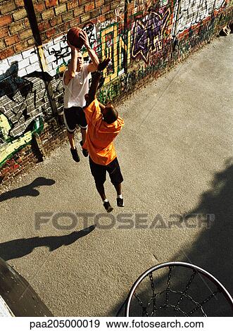 Man shooting basketball, opponent jumping, in urban playground View Large Photo Image Stock Photo - Man shooting basketball, opponent jumping, in urban playground. Fotosearch