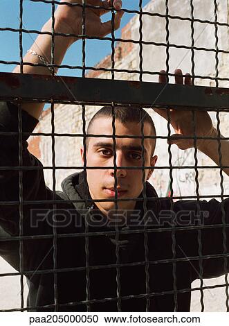 Man standing behind fence, looking at camera, portrait View Large Photo Image Stock Image - Man standing behind fence, looking at camera, portrait. Fotosearch