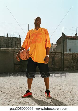 Man standing with a basketball in urban playground View Large Photo Image Stock Photograph - Man standing with a basketball in urban playground. Fotosearch
