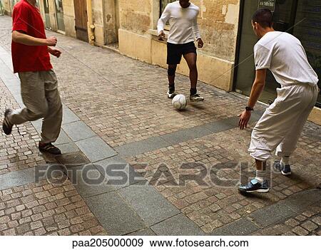 Men kicking soccer ball in street View Large Photo Image Stock Photo - Men kicking soccer ball in street. Fotosearch