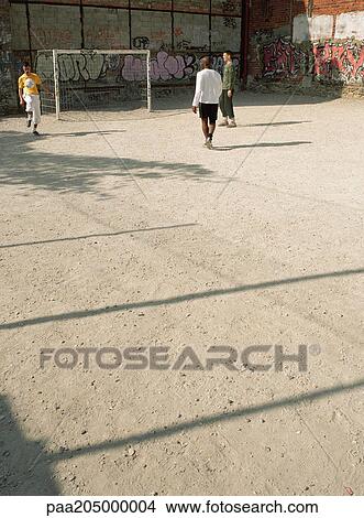 Men kicking soccer ball on dirt field View Large Photo Image Picture - Men kicking soccer ball on dirt field. Fotosearch