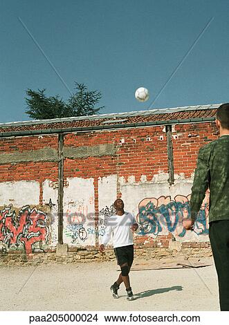 Men playing with soccer ball in urban setting View Large Photo Image Picture - Men playing with soccer ball in urban setting. Fotosearch