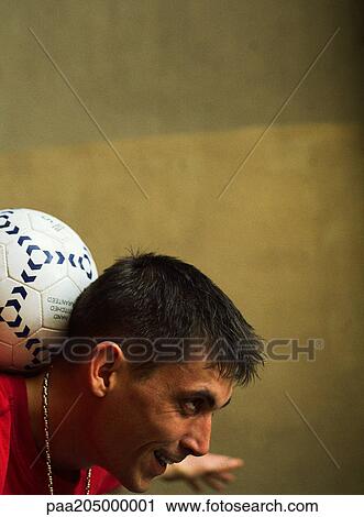 Stock Image - Profile of man balancing soccer ball on back of neck. Fotosearch