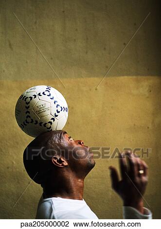 Profile view of man balancing soccer ball on head View Large Photo Image Stock Image - Profile view of man balancing soccer ball on head. Fotosearch