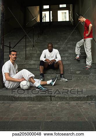 Three men sitting on steps with soccer ball View Large Photo Image Stock Photo - Three men sitting on steps with soccer ball. Fotosearch