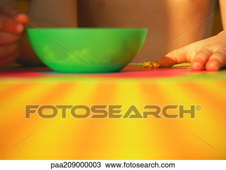 Stock Image - Green bowl on a table, child in background. Fotosearch