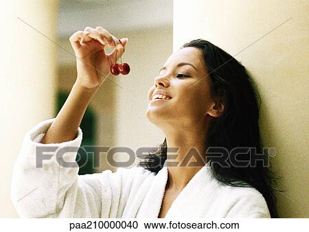 Stock Image - Woman holding up cherries.. Fotosearch