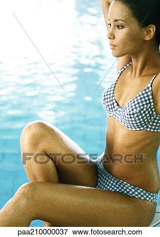 Woman wearing bikini sitting by swimming pool. View Large Photo Image Stock Photo - Woman wearing bikini sitting by swimming pool.. Fotosearch