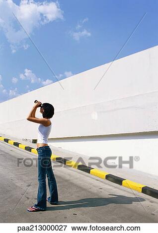 Woman on road looking at sky with binoculars View Large Photo Image Stock Photo - Woman on road looking at sky with binoculars. Fotosearch
