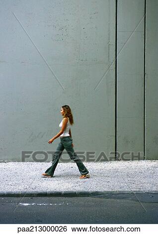 Woman walking on sidewalk, side view View Large Photo Image Stock Photograph - Woman walking on sidewalk, side view. Fotosearch