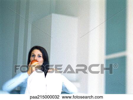 Stock Image - Woman eating apple, slightly blurred.. Fotosearch