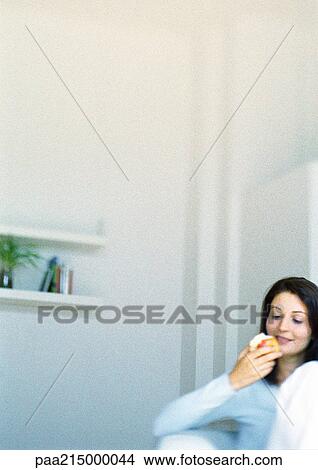Woman eating apple, smiling. View Large Photo Image Picture - Woman eating apple, smiling.. Fotosearch