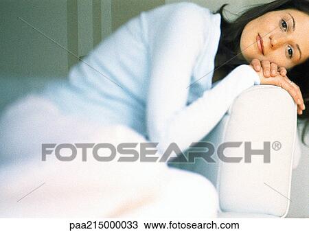 Woman in armchair, leaning head on chair arm, looking at camera View Large Photo Image Stock Image - Woman in armchair, leaning head on chair arm, looking at camera. Fotosearch