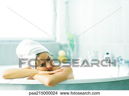 Woman in bathtub leaning on edge of tub, hair wrapped in towel View Large Photo Image Picture - Woman in bathtub leaning on edge of tub, hair wrapped in towel. Fotosearch