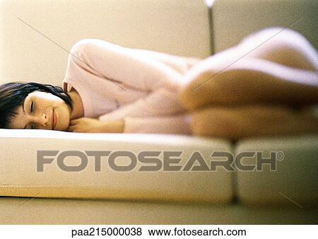 Woman lying curled up on sofa, eyes closed. View Large Photo Image Stock Photo - Woman lying curled up on sofa, eyes closed.. Fotosearch