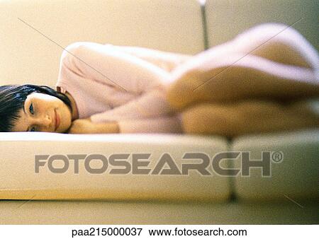 Woman lying curled up on sofa, smiling. View Large Photo Image Stock Photo - Woman lying curled up on sofa, smiling.. Fotosearch