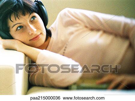 Woman lying on sofa, listening to headphones, close-up. View Large Photo Image Stock Photograph - Woman lying on sofa, listening to headphones, close-up.. Fotosearch