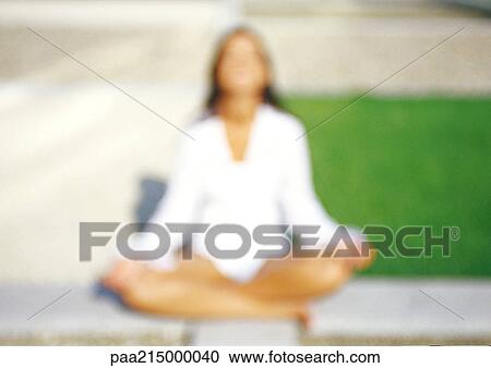 Stock Image - Woman sitting in Lotus position, defocused. Fotosearch