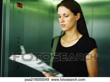 Woman reading newspaper in elevator. View Large Photo Image Stock Photo - Woman reading newspaper in elevator.. Fotosearch
