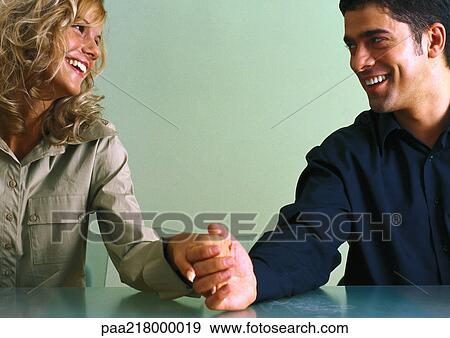 Couple holding hands at table, smiling at each other View Large Photo Image Stock Photo - Couple holding hands at table, smiling at each other. Fotosearch