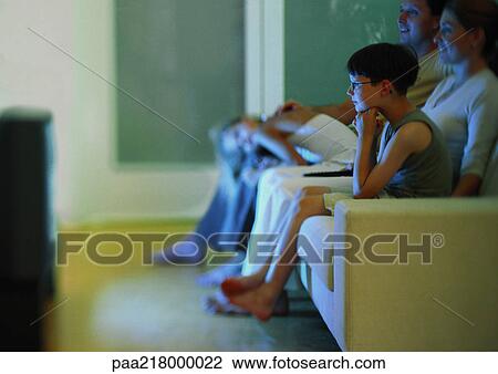 Family watching television on sofa, side view View Large Photo Image Stock Image - Family watching television on sofa, side view. Fotosearch