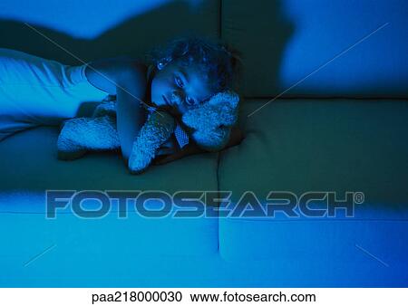 Little girl lying on sofa in dark, holding teddy bear View Large Photo Image Stock Image - Little girl lying on sofa in dark, holding teddy bear. Fotosearch