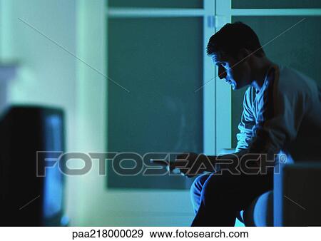 Man sitting and watching television, holding remote control, side view View Large Photo Image Stock Photo - Man sitting and watching television, holding remote control, side view. Fotosearch