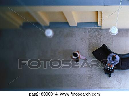 Man using laptop and woman walking toward man, elevated view. View Large Photo Image Picture - Man using laptop and woman walking toward man, elevated view.. Fotosearch