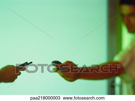 Stock Image - Two people holding cell phones.. Fotosearch