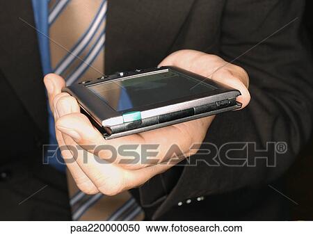 Stock Image - Businessman holding electronic organizer, close-up.. Fotosearch
