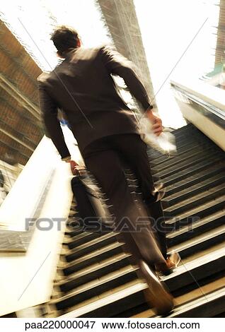 Stock Photo - Businessman walking up stairs, blurred.. Fotosearch