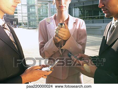 Picture - Businessmen and a businesswoman using cell phones.. Fotosearch