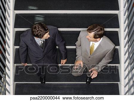 Picture - Two businessmen going down stairs, elevated view.. Fotosearch