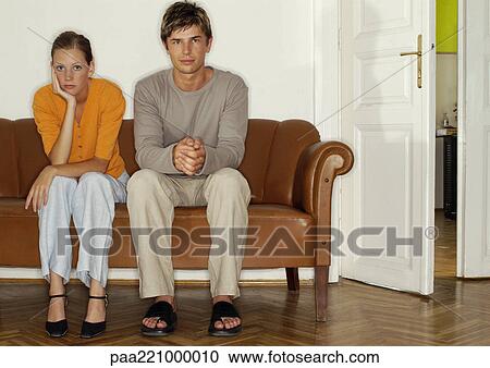Man and woman sitting side by side on sofa View Large Photo Image Stock Image - Man and woman sitting side by side on sofa. Fotosearch