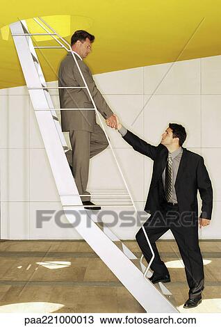 Two men standing on ladder, shaking hands View Large Photo Image Stock Image - Two men standing on ladder, shaking hands. Fotosearch