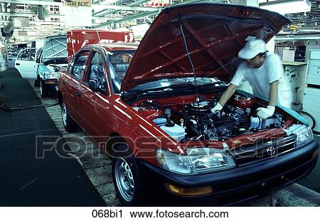 Stock Image - Car Assembly Worker Under Bonnet. Fotosearch