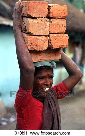 Stock Image - Indian Woman Labourer Carrying Bricks on Head India. Fotosearch