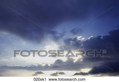 Stock Image - Sun behind Blue Clouds. Fotosearch