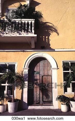 Stock Image - Arched Wooden Door in Yellow Wall. Fotosearch