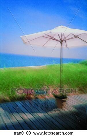 Stock Image - bay, blue sky, blue water, chairs, deck, flower pot, holiday. Fotosearch