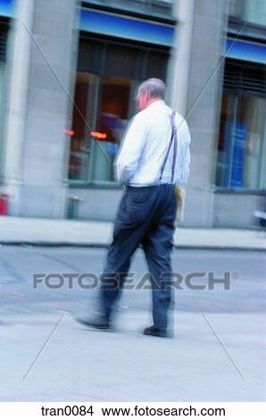 Picture - man in suspenders, building, elderly man, elderly, city, aging. Fotosearch