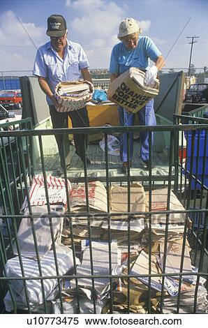 A couple throwing newspaper bundles into a bin to be recycled View Large Photo Image Stock Photography - A couple throwing newspaper bundles into a bin to be recycled. Fotosearch