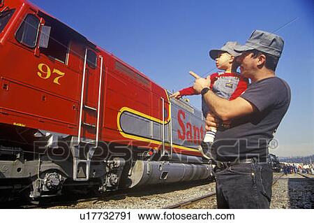 Stock Image - A father and son in engineer caps look at a historic Santa Fe diesel train. Fotosearch